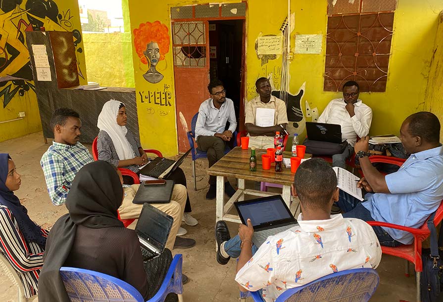 Meeting participants sitting in circular formation engage in a discussion.