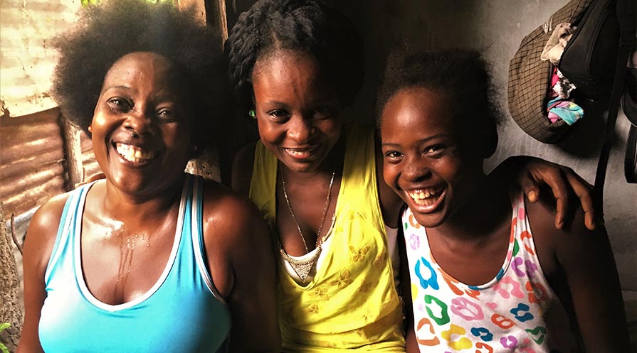 Antoinette Sainfabe (right) lives with her daughter and niece, as well as two sons, in her rebuilt home in Léogâne, Haiti. The house replaced the one that collapsed on top of Sainfabe during the 2010 earthquake.