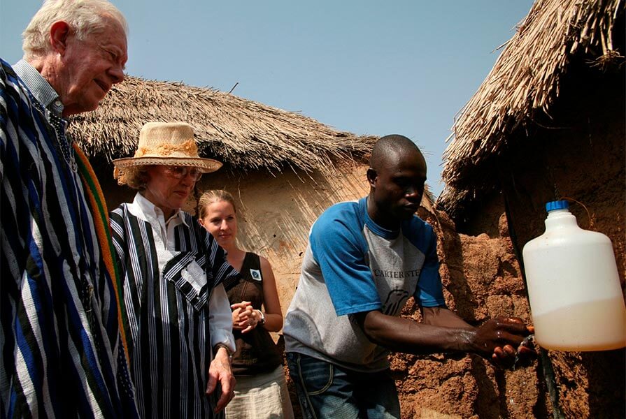 Health worker Fusheni Nazeed demonstrates for President and Mrs. Carter how trachoma can be prevented when simple environmental strategies and health education become part of people's daily lives in the village of Tingoli, Ghana, in 2007. Ghana is the first sub-Saharan African country to be validated by the World Health Organization for eliminating the eye disease trachoma as a public health problem. (Photo: The Carter Center)