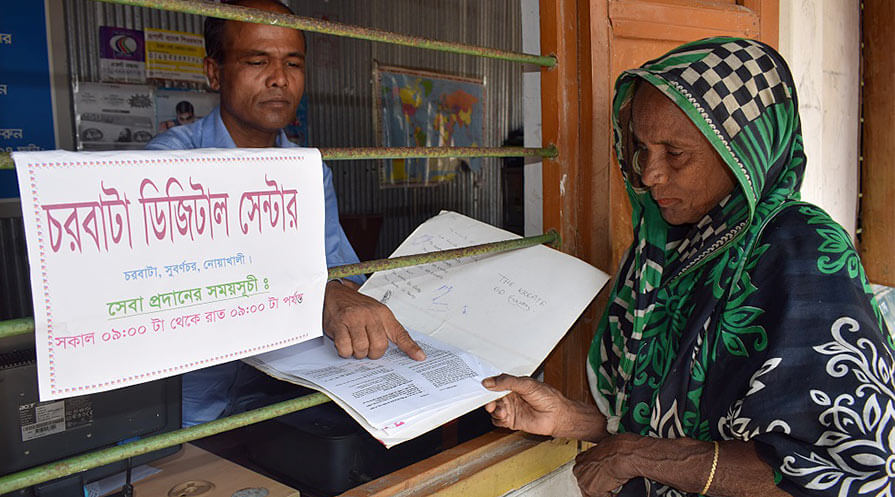 Man behind a counter shows document to a woman.